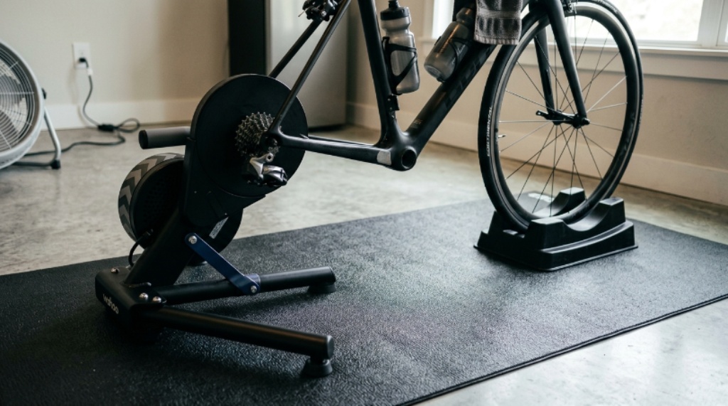 Close-up of a sweat-resistant cycling mat with a turbo trainer and riser block positioned on top